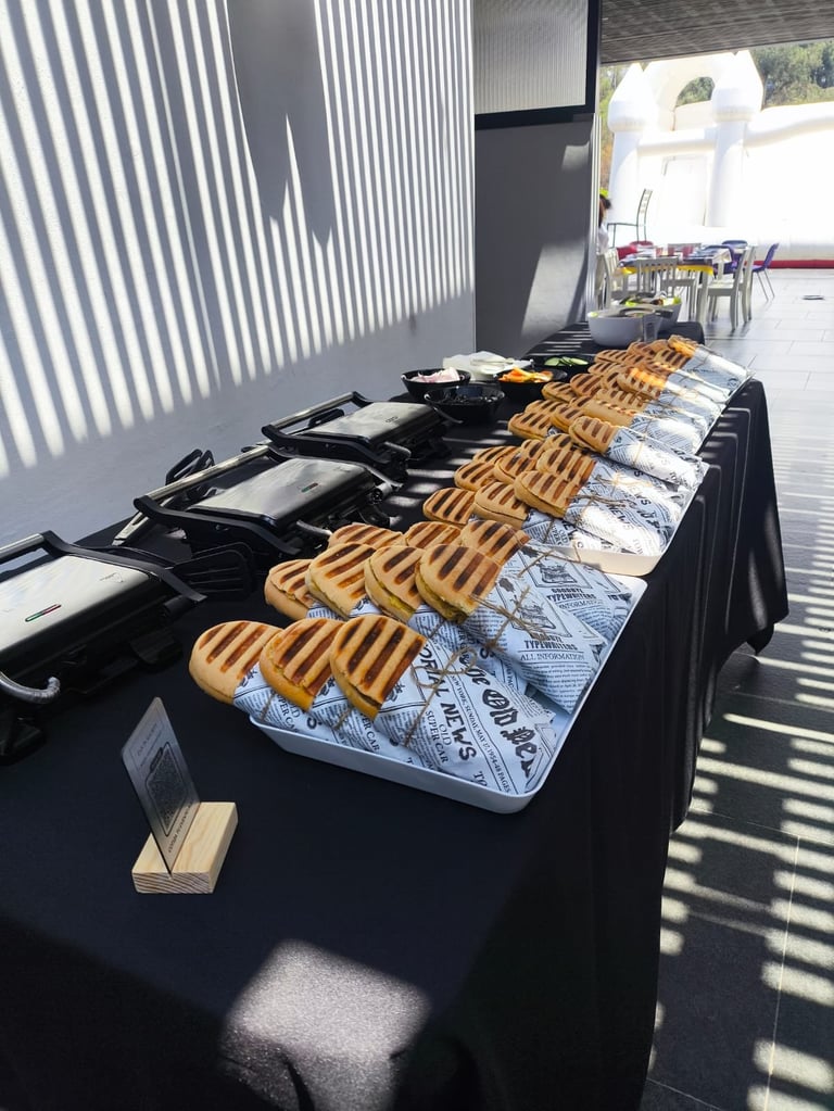 Display table with woven placemats and black kitchen items arranged in a row at an outdoor event or market